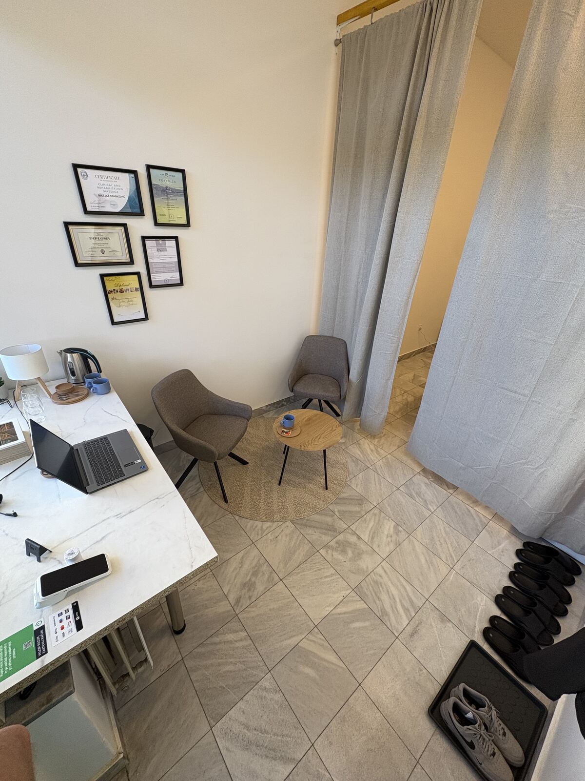 The waiting area with armchairs, a small table and framed certificates